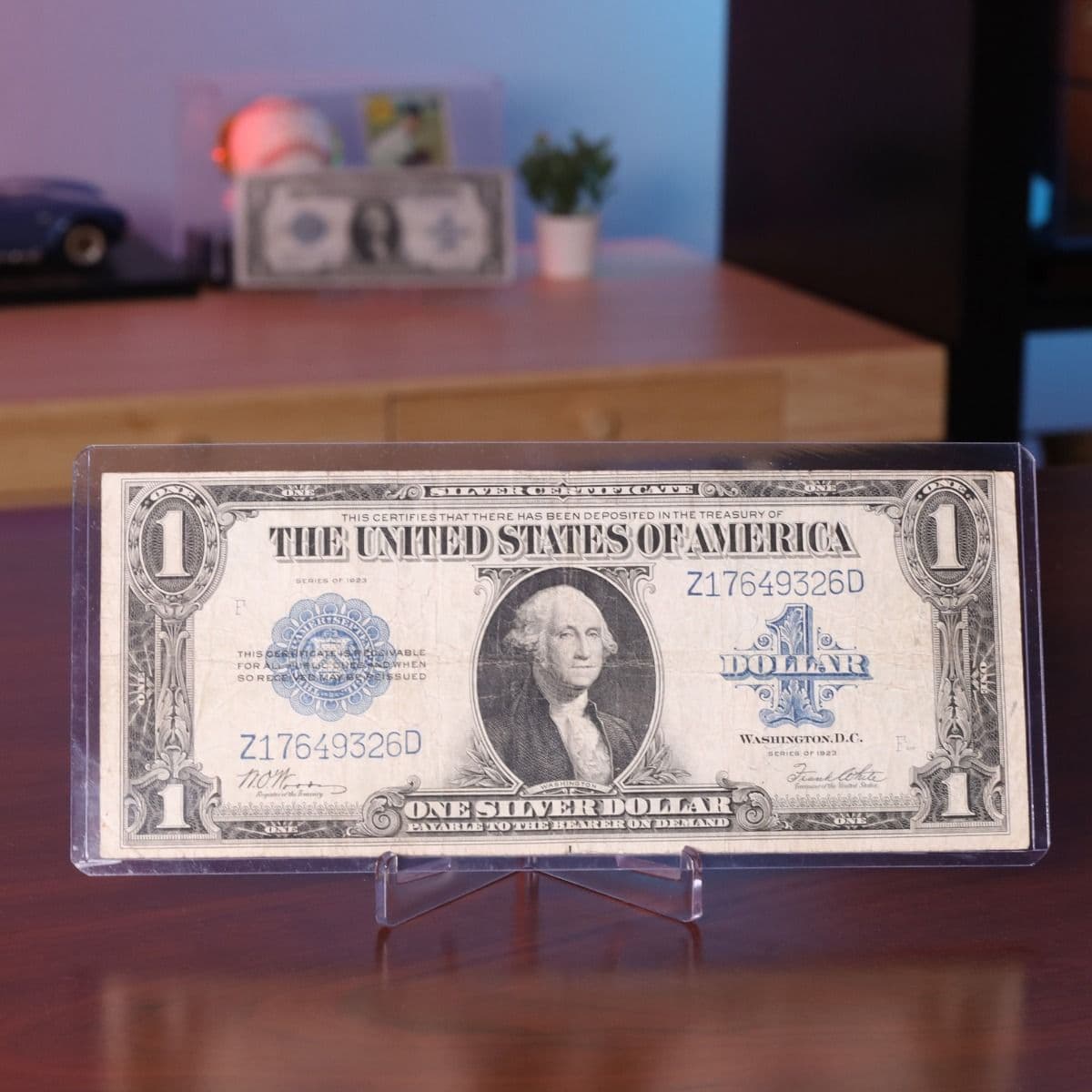 Oversized one-dollar bill displayed in a clear BCW currency holder on a tabletop stand for protected presentation and display.