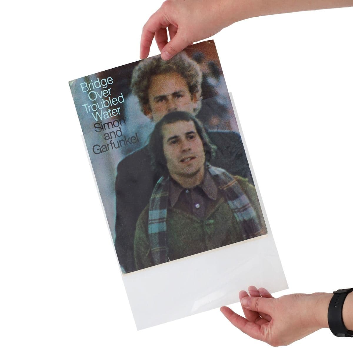 Hands demonstrate inserting a sheet music booklet into a BCW Sheet Music Sleeve, showing the easy-loading design that helps protect and preserve collectible music scores.