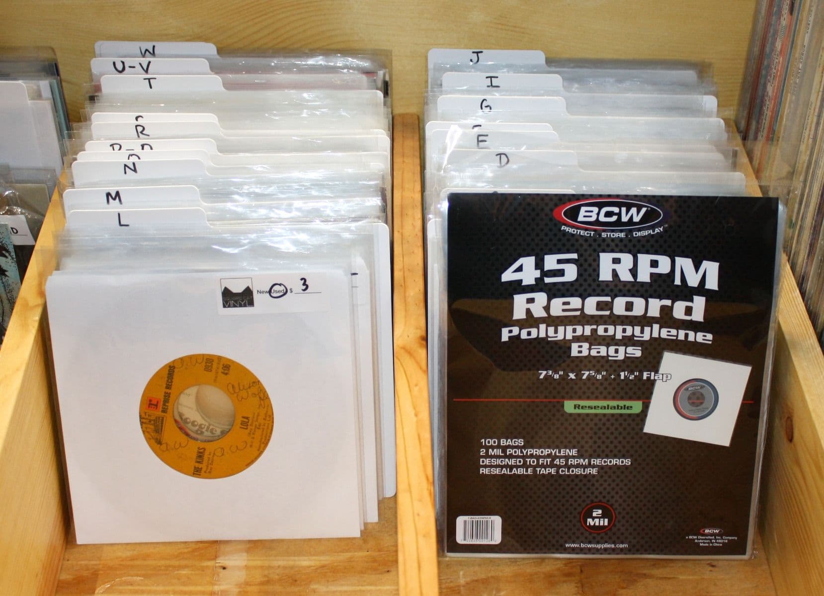 Several records inside Resealable 45 RPM Record Bags next to package of BCW Resealable 45 RPM Record Bags