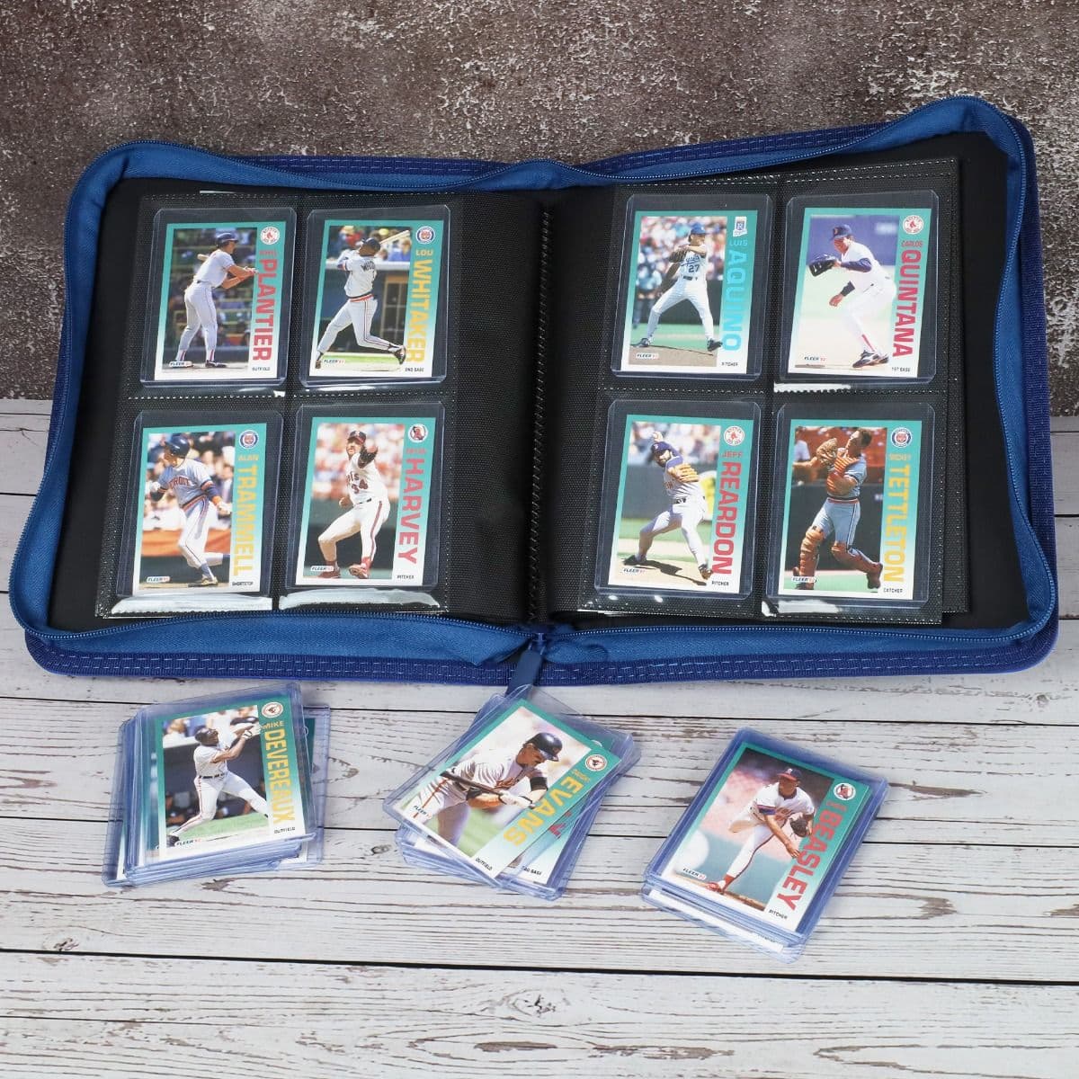 BCW Z-Folio 4-Pocket LX Album - Toploaders - Blue displayed on a tabletop, opened with pages full of cards, surrounded by toploaded cards