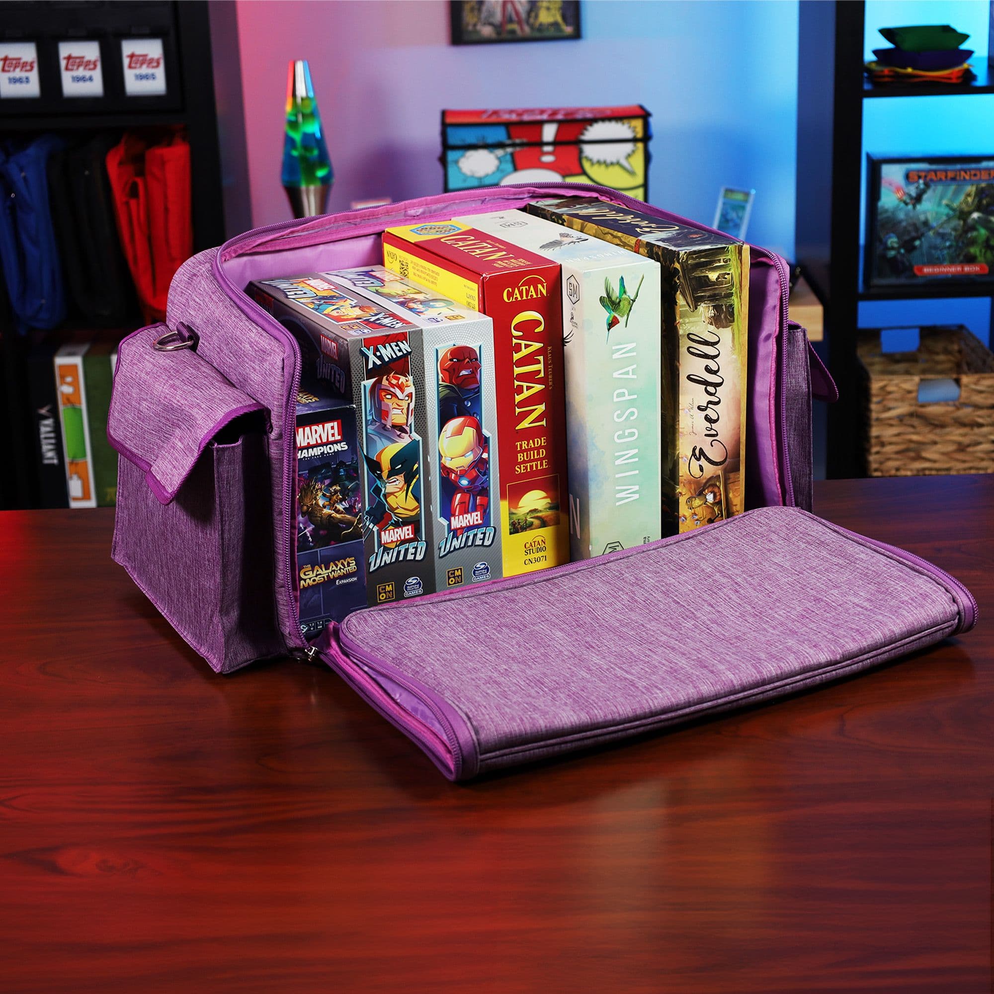 the BCW Board Game Bag in purple, positioned on a wooden tabletop in a game room setting. The bag's top is partially open, displaying several board games inside.