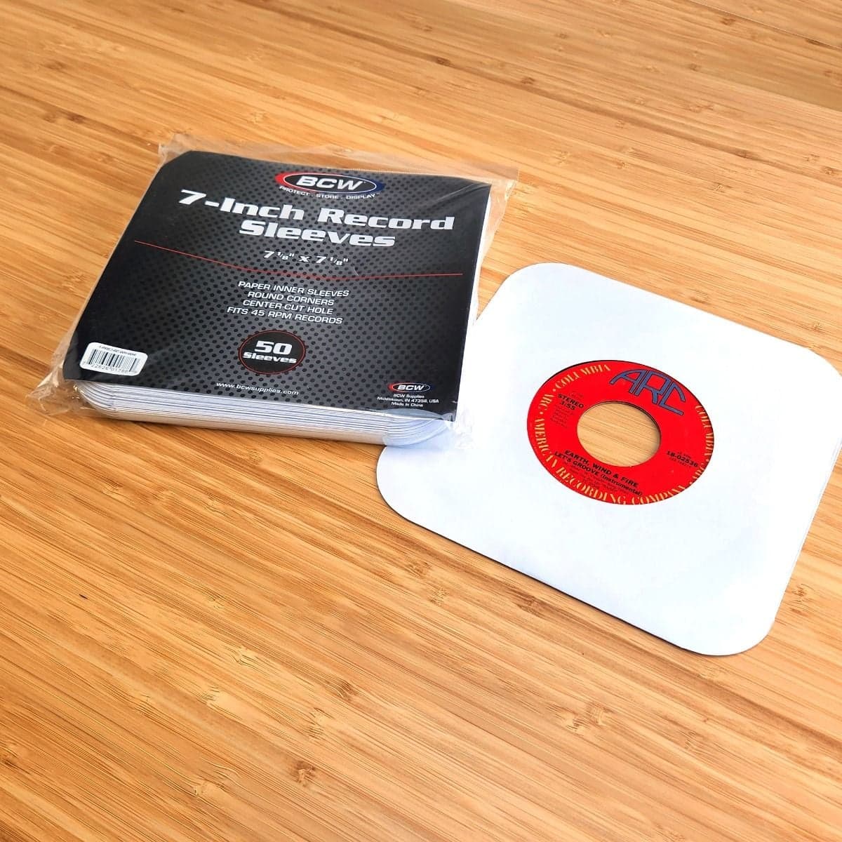 Package of BCW 7 Inch Record Paper Inner Sleeves - Round Corners - With Hole - White next to record in sleeve