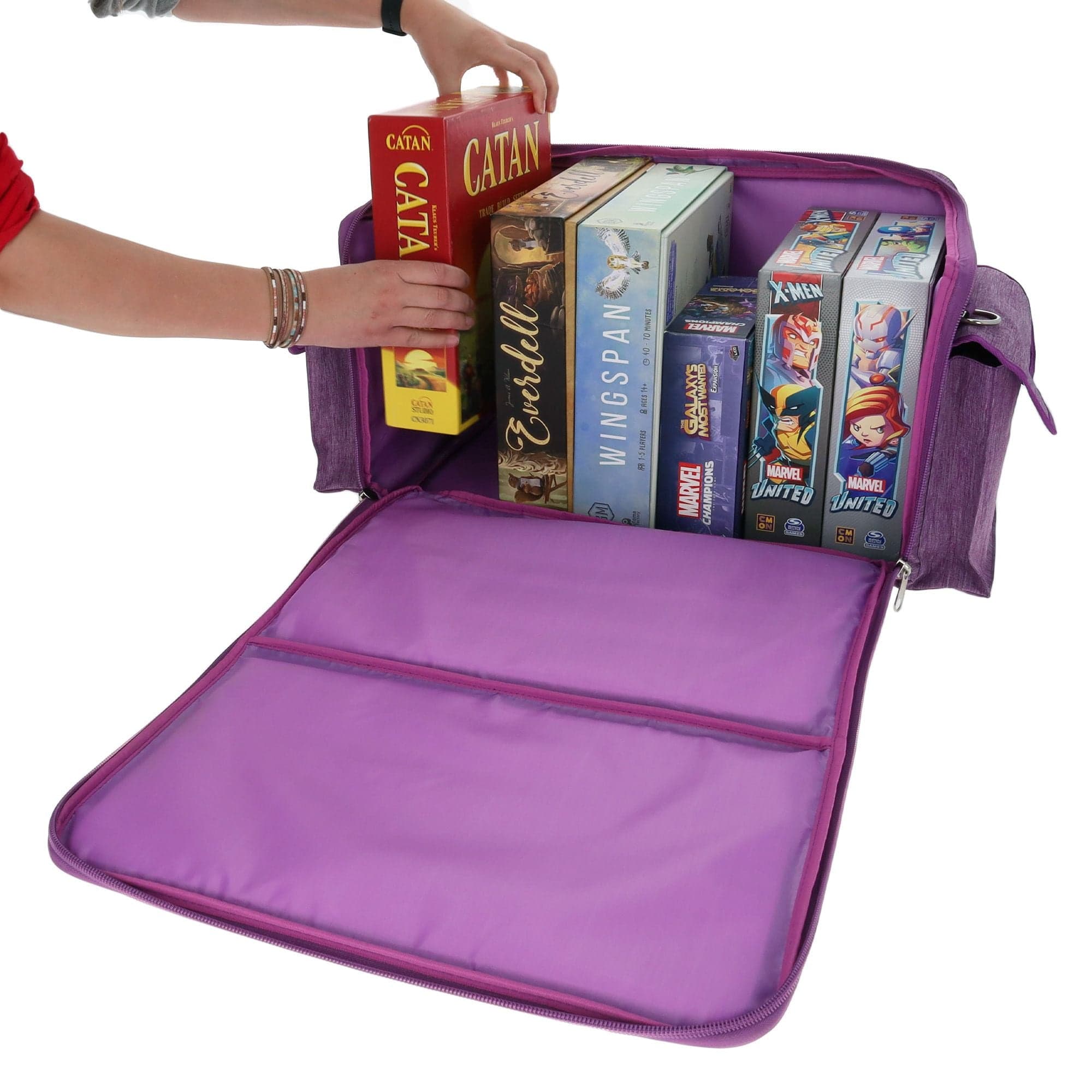 purple BCW Board Game Bag being used to store several board games. The bag's top is unzipped and laid open, revealing the interior space, which can accommodate approximately six to eight standard-sized board games. A person is pulling a board game out of