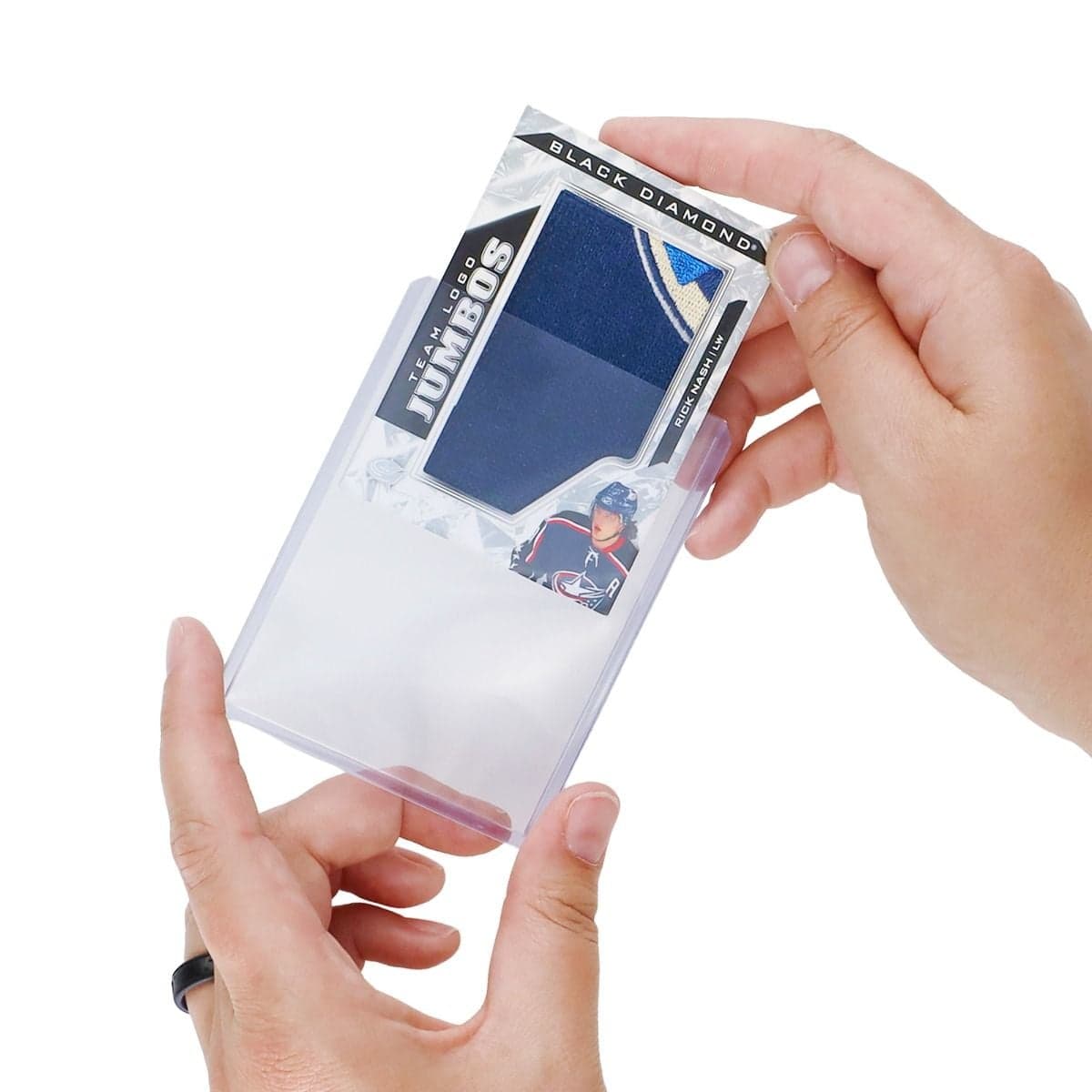 Hands inserting an extra-thick patch trading card into a BCW 168 PT 3 x 4 toploader, demonstrating the secure fit for protecting thick memorabilia cards.