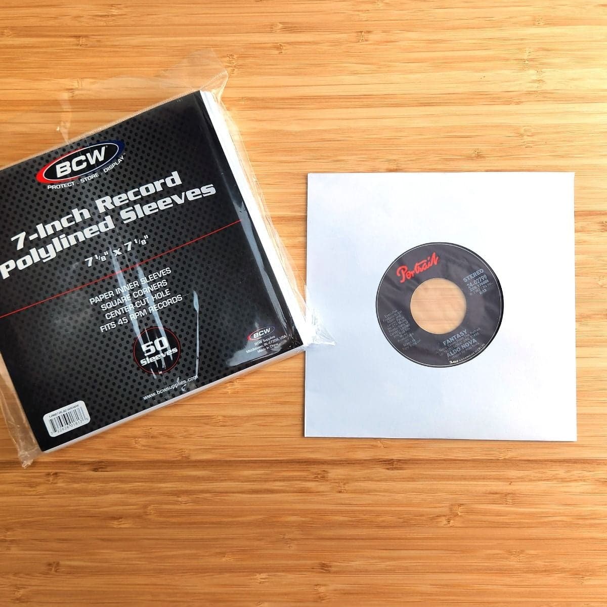 Package of BCW 7 Inch Record Paper Inner Sleeves - Polylined - With Hole - White next to record in sleeve
