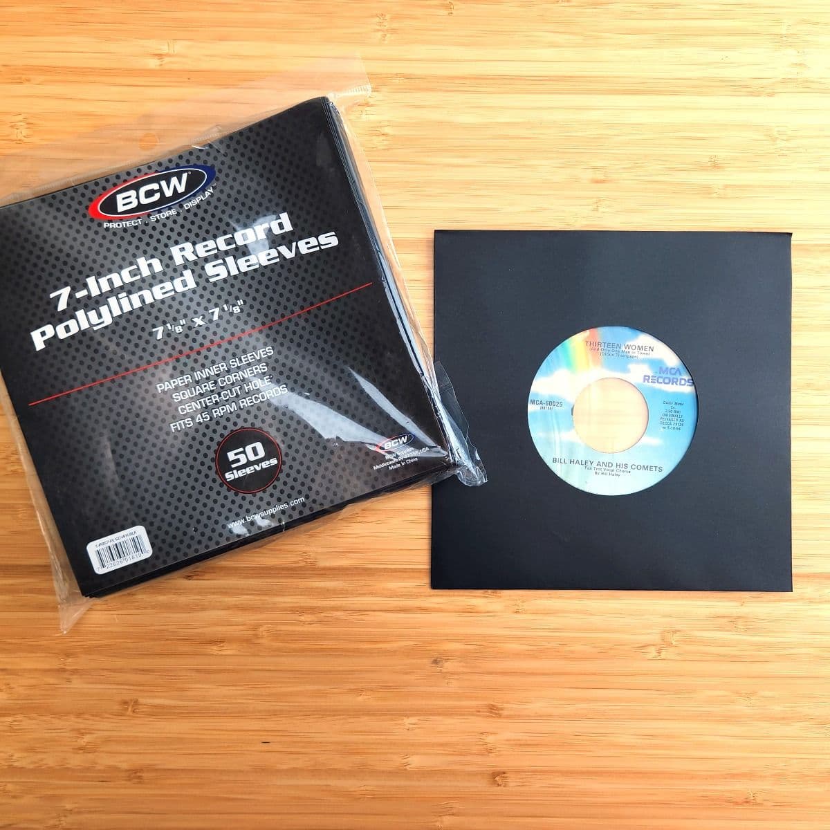 Package of BCW 7 Inch Record Paper Inner Sleeves - Polylined - With Hole - Black next to record in sleeve