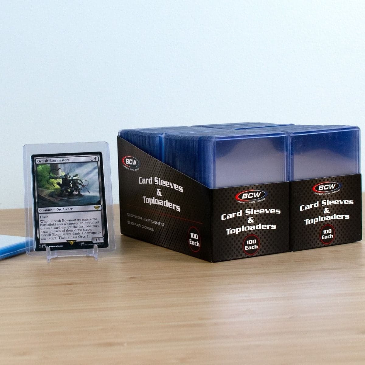 200 Count Card Sleeve and Toploader Combo Pack. Packaging group with gaming card in sleeve and toploader on clear stand