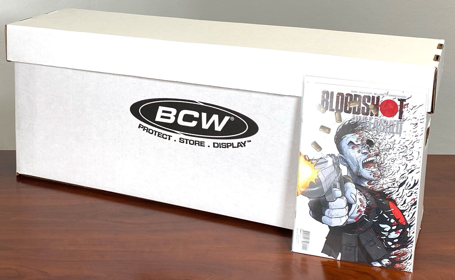 1 BCW Long Comic box assembled on table with 1 comic in a BCW Comic Bag with a backing board leaning against the box