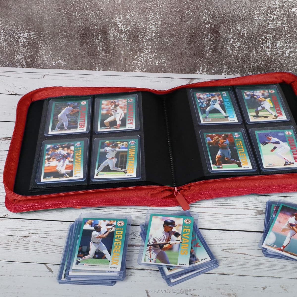 BCW Z-Folio 4-Pocket LX Album - Toploaders - Red displayed on a tabletop, opened with pages full of cards, surrounded by toploaded cards