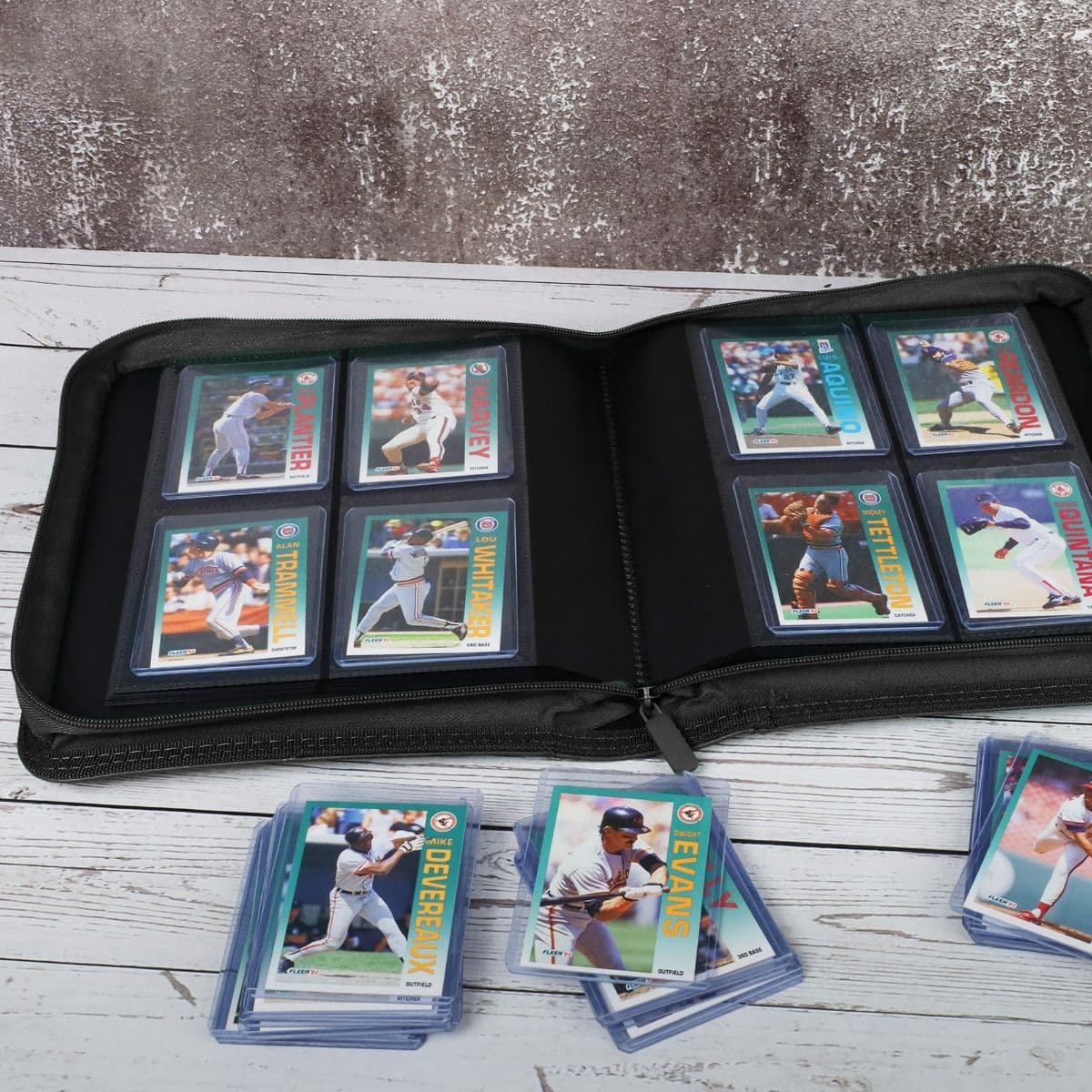 BCW Z-Folio 4-Pocket LX Album - Toploaders - Black displayed on a tabletop, opened with pages full of cards, surrounded by toploaded cards
