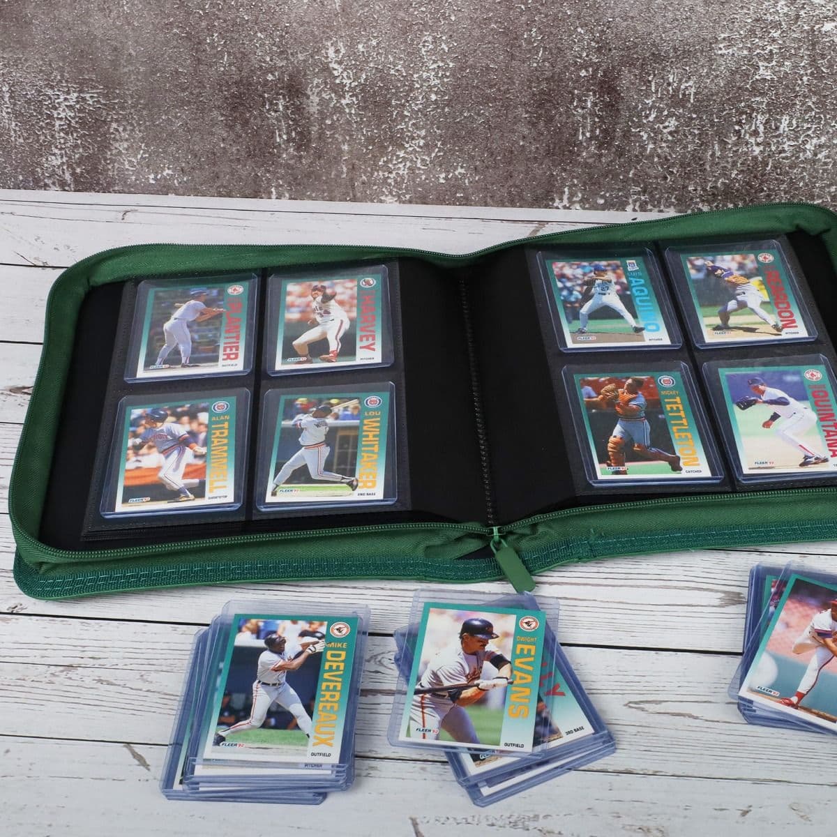 BCW Z-Folio 4-Pocket LX Album - Toploaders - Green displayed on a tabletop, opened with pages full of cards, surrounded by toploaded cards
