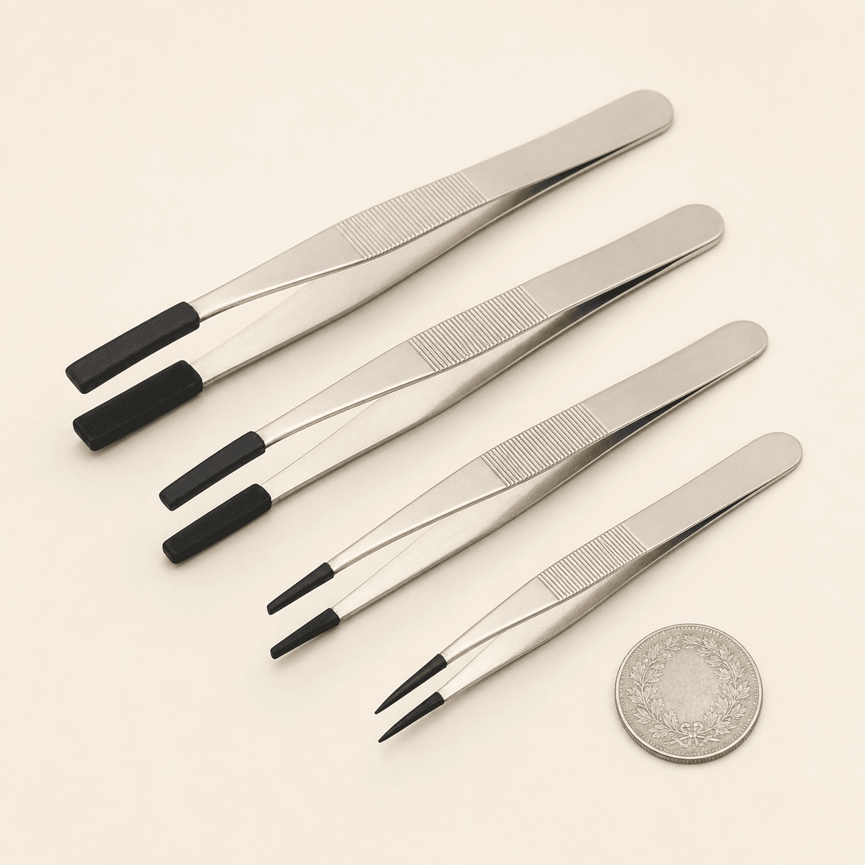 Original representative image of four metal coin-handling tweezers with soft black tips.
